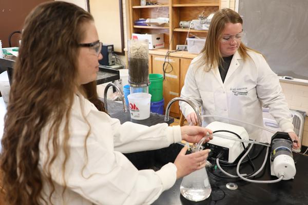 Two female students using environmental equipment in a lab
